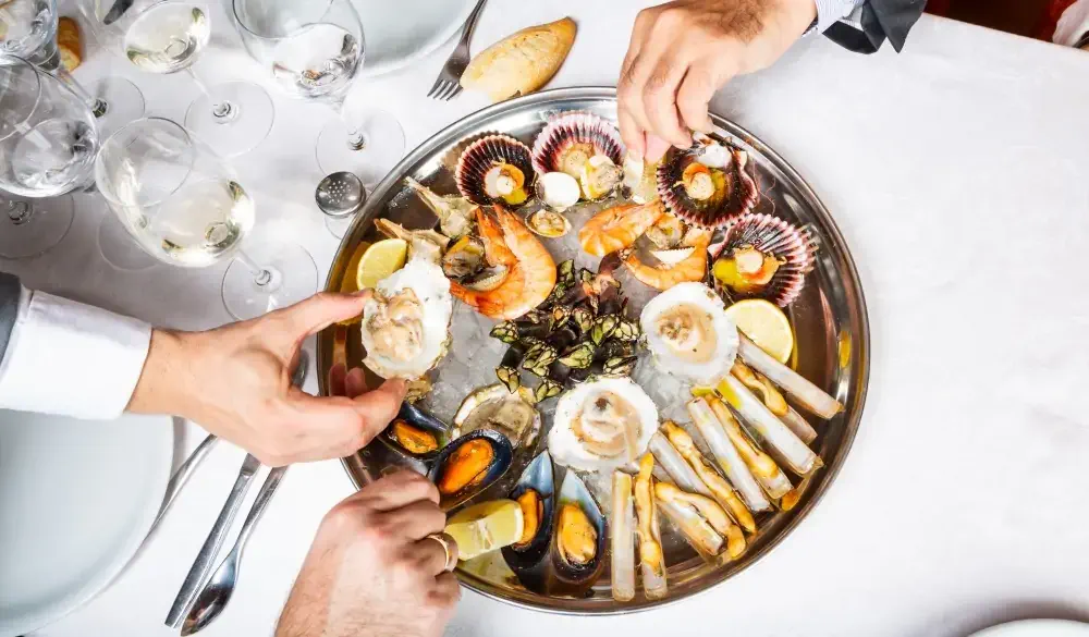 View from above of seafood plate and male hands picking food