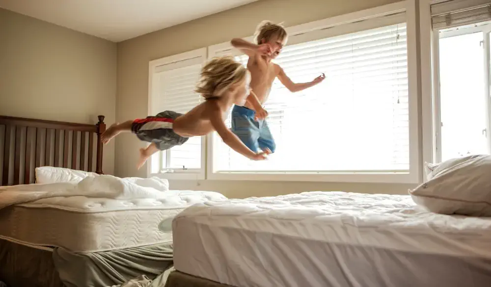 Caucasian boys jumping on beds