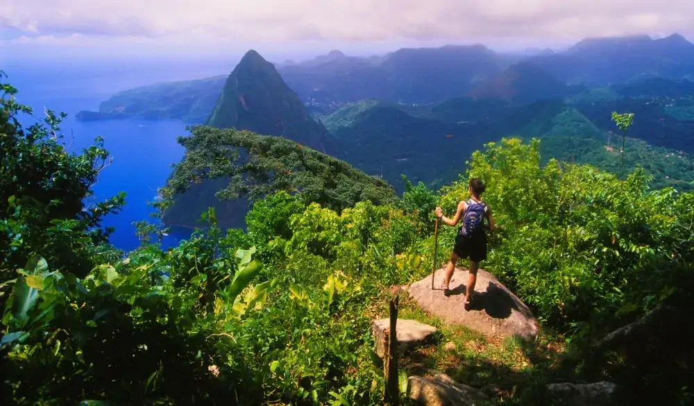 A hiker admires the view of Petit Piton from the top of Gros Piton. The two volcanic mountains make up The Pitons in St. Lucia, and are linked by the Piton Mitan ridge.