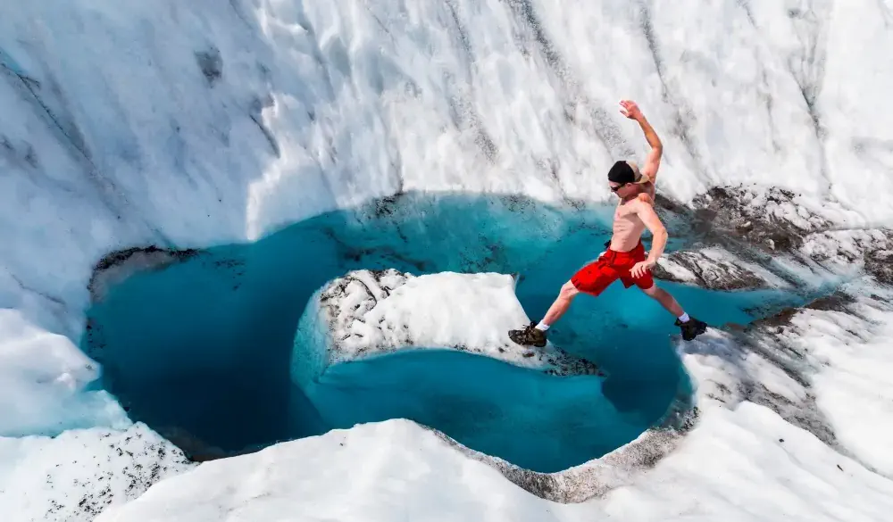 A man jumps onto an island of ice on Root Glacier in Wrangell-St. Elias National Park